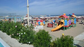 Una playa con un parque infantil, una piscina y un cielo despejado.