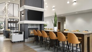 A modern kitchen with a built-in fireplace, a dining area with bar stools, and a large window. - Larkspur Landing Hotel South Bend (South Bend)