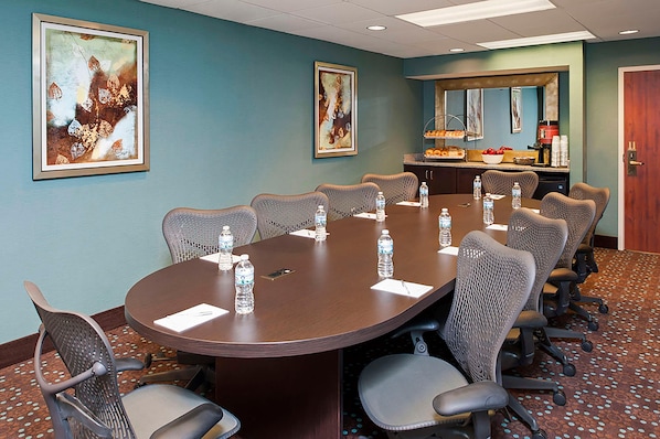 A conference room with a large table, chairs, water bottles, and artwork on the walls. - Larkspur Landing Hotel South Bend (South Bend)