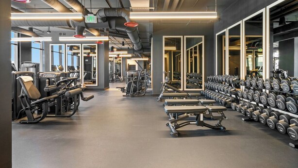 A gym with exercise equipment, weight racks, and a mirrored wall. - The E11EVEN Hotel & Residences (Miami)