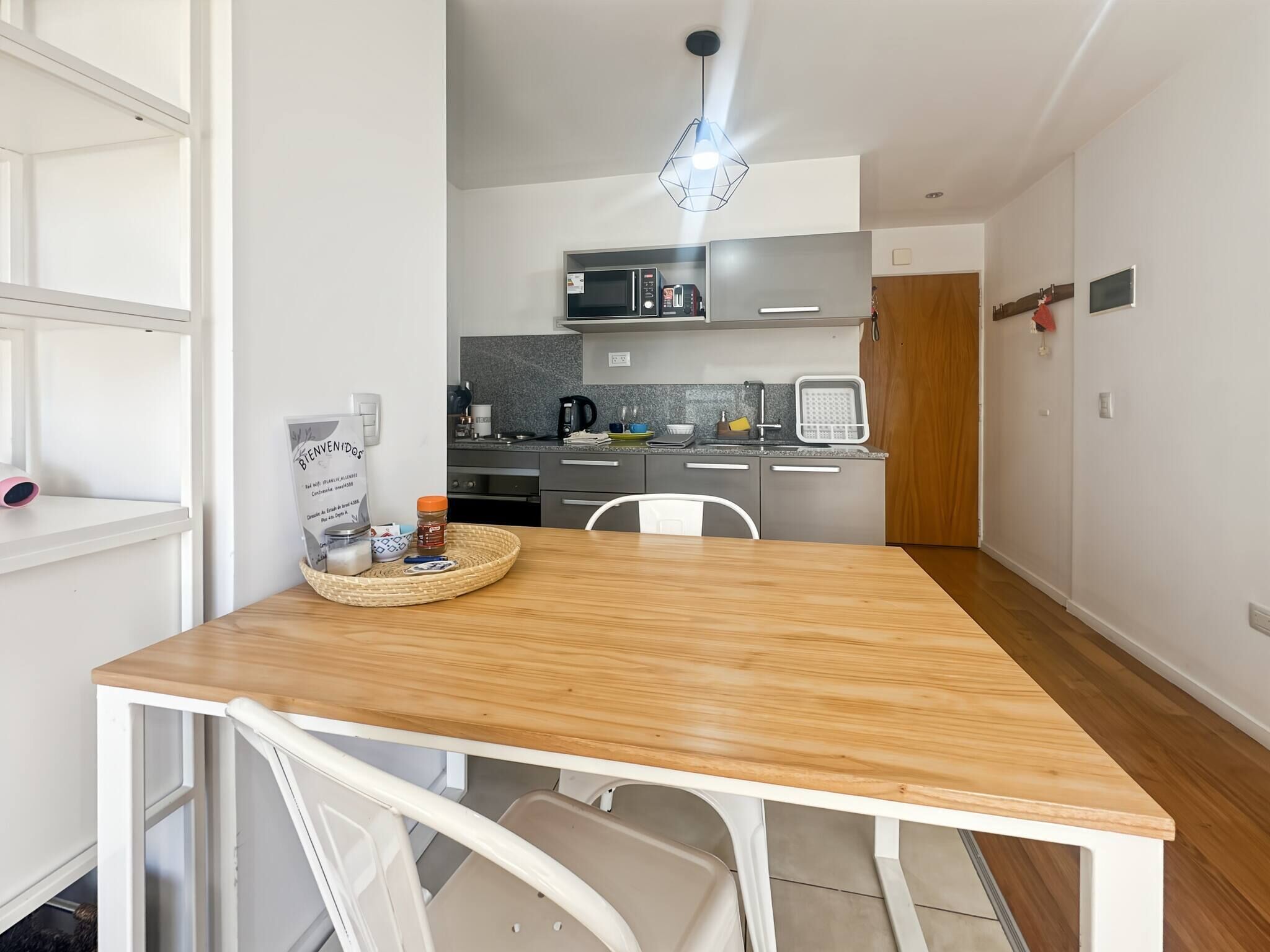 A modern kitchen with a microwave, coffee maker, and a hanging light fixture.