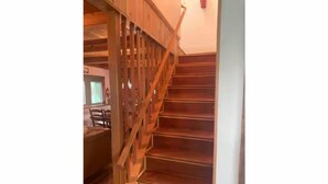Una escalera de madera con barandilla que lleva a un piso superior.