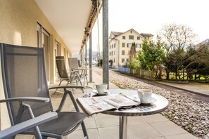 En utomhusplats med sittplatser, bord, en tidning och en kopp.