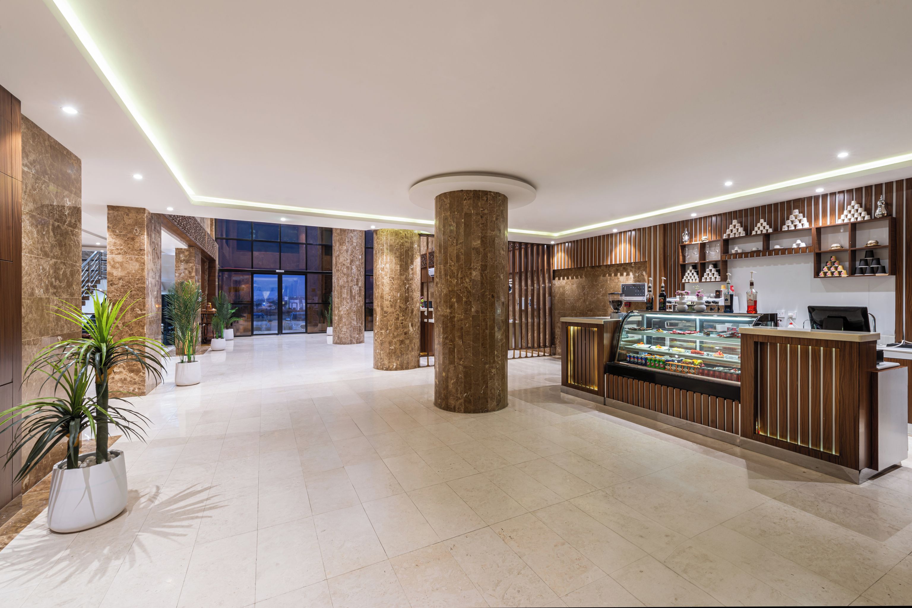 A hotel lobby with marble columns, a reception desk, and a food display.
