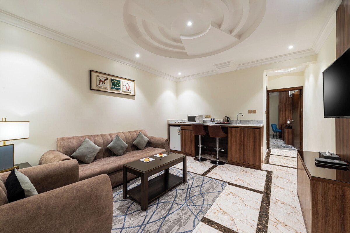 Una sala de estar con sofá, mesa de centro y una zona de cocina con mostrador y sillas.