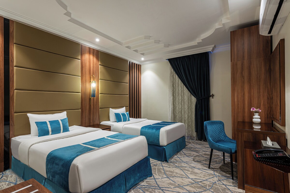 Una habitación de hotel con dos camas, un escritorio, una silla y una zona de recepción.