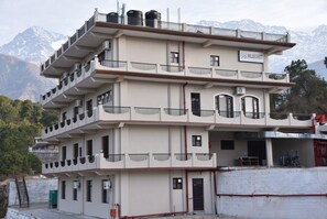 A multi-story building with balconies, a sign reading 'WILDECREST,' and a mountainous backdrop. - Mastiff Wildcrest Dharamshala by Othpl (Palampur)