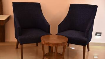 Dos sillones azul oscuro con patas de madera y una mesita redonda de madera en el centro.