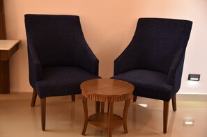 Two dark blue armchairs with wooden legs and a small round wooden table between them. - Mastiff Wildcrest Dharamshala by Othpl (Palampur)
