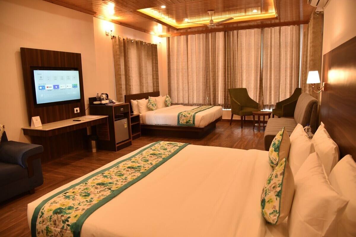 A hotel room with a bed, a desk, a chair, a television, and curtains.