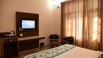 A hotel room with a bed, a desk, a chair, a television, and curtains.