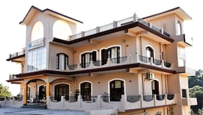 A multi-story building with balconies, a prominent arched entrance, and a sign reading 'WILDECREST.' - Mastiff Wildcrest Dharamshala by Othpl (Palampur)