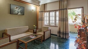 A hotel lobby with a sofa, armchair, coffee table, and a painting on the wall. - Eagleton The Golf Resort (Ramanagara)