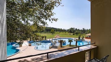 A pool area with a gazebo, lounge chairs, and a view of a green landscape.
