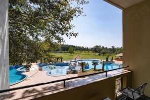 A pool area with a gazebo, lounge chairs, and a view of a green landscape. - Eagleton The Golf Resort (Ramanagara)
