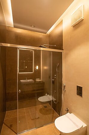 A modern bathroom with a glass-enclosed shower, a sink, and a toilet. - Eagleton The Golf Resort (Ramanagara)
