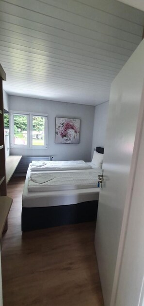 A bedroom with a bed, a window, and a radiator. - The River Village (Interlaken)