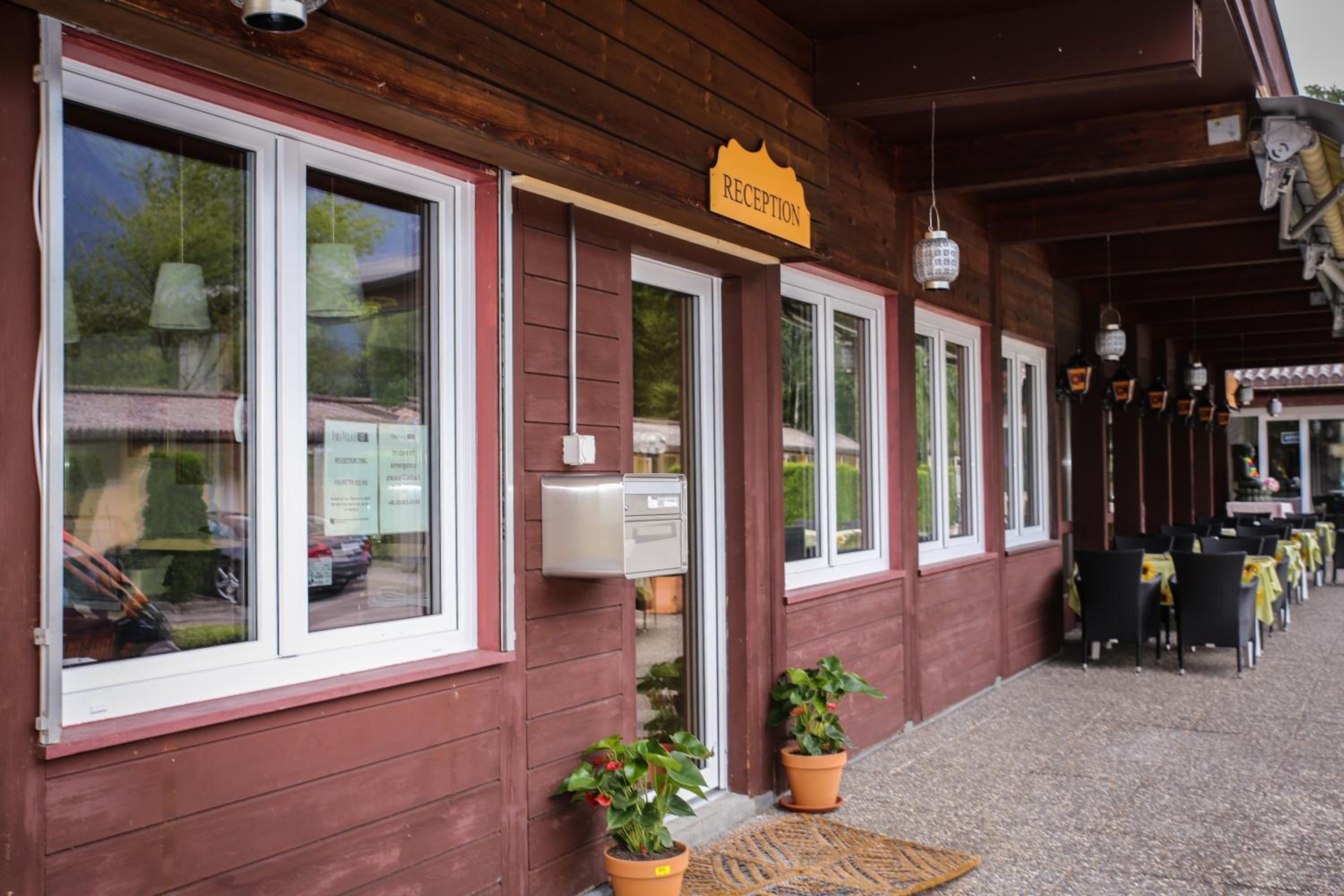 Un bâtiment en bois avec une enseigne indiquant l’accueil, des fenêtres et des sièges à l’extérieur.