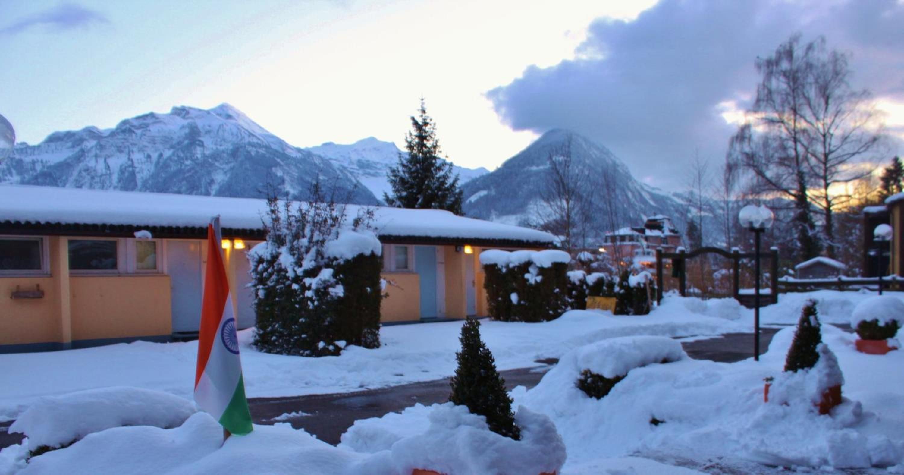 Ein Gebäude mit verschneitem Dach, einer Flagge und einer Bergkulisse im Hintergrund.