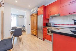 Eine moderne Küche mit roten Schränken, Edelstahlgeräten und einem Essbereich mit Holztisch und Stühlen.