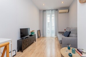 Ein modernes Wohnzimmer mit einer Couch, einem Fernseher, einem Holzschrank und einem Couchtisch.