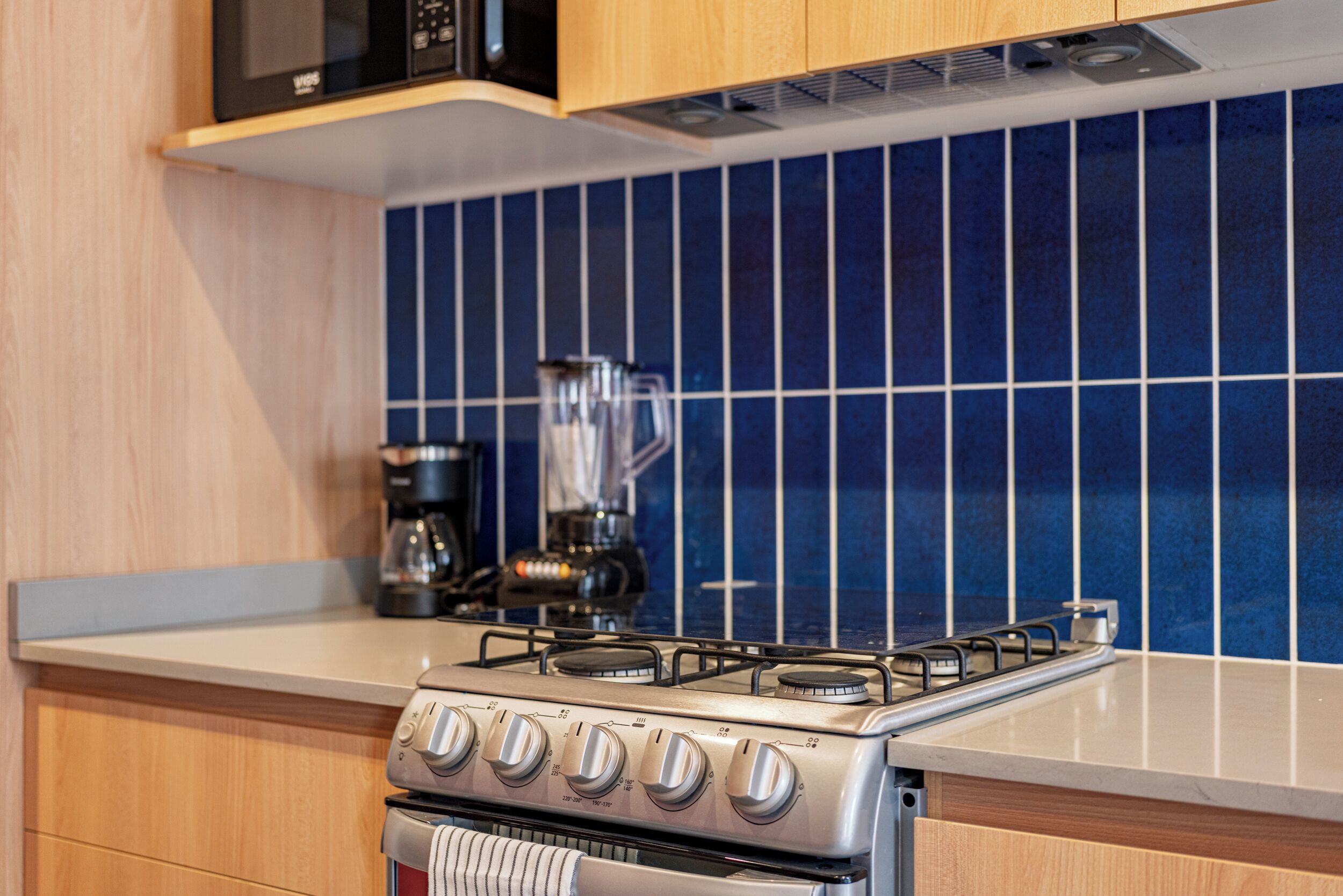 A kitchen with a gas stove, a coffee maker, and a blender on the counter.