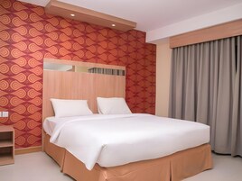 Una habitación de hotel con una cama grande, cabecera de madera, pared con diseño y una ventana con cortinas.