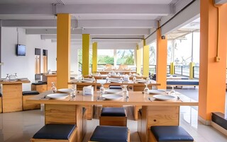 Un comedor moderno con varias mesas y bancos, ventanas amplias y vista a espacios verdes al exterior.