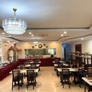 Ein Restaurant mit mehreren Tischen, Stühlen und einer Chandelüster.