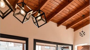A room with a wooden ceiling, a table with a vase, and a view through a glass door. - Lujoso amplio dpto para 8 en Salta con cochera (Salta)