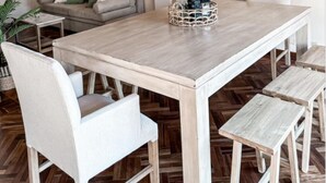 A dining area with a wooden table, white chairs, and a hanging light fixture. - Lujoso amplio dpto para 8 en Salta con cochera (Salta)