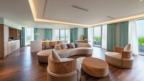 A spacious living area with a curved sofa, round wicker ottomans, and a dining table with chairs. - Bellerive Hoi An Resort & Spa (Da Nang Municipality)