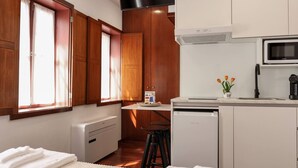 Une cuisine compacte avec des meubles en bois, un four à micro-ondes, un petit réfrigérateur et une fenêtre avec des rideaux.