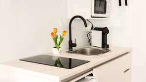 Une cuisine moderne dotée d’un four à micro-ondes encastré, d’un robinet noir et d’une petite plante en pot posée sur le plan de travail.