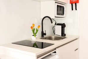 Een moderne keuken met een inbouwmagnetron, een zwarte kraan en een kleine potplant op het aanrecht.