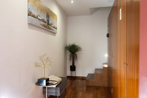 Een hal met een trap, een potplant, een decoratieve boom en een schilderij aan de wand.