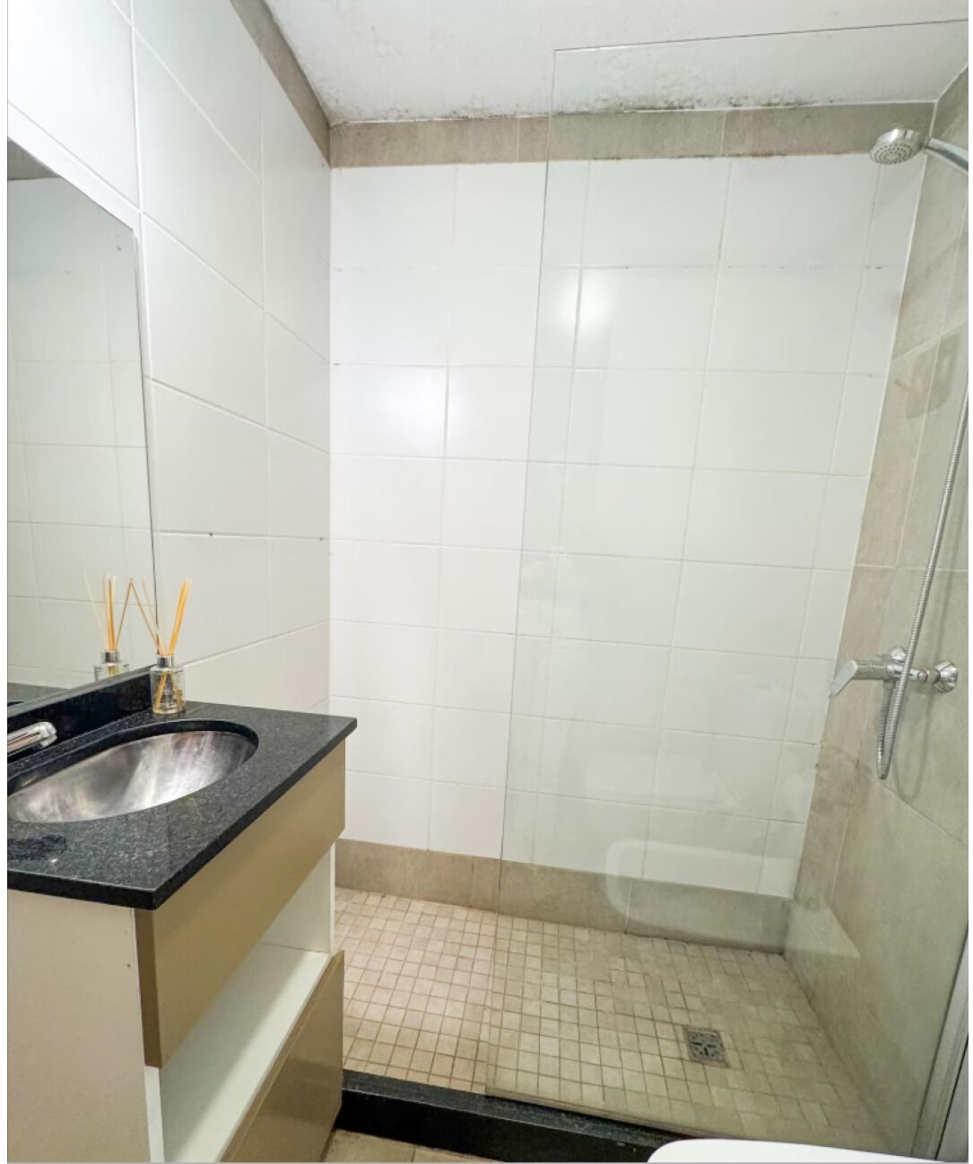 Un bagno con doccia, lavandino e specchio.