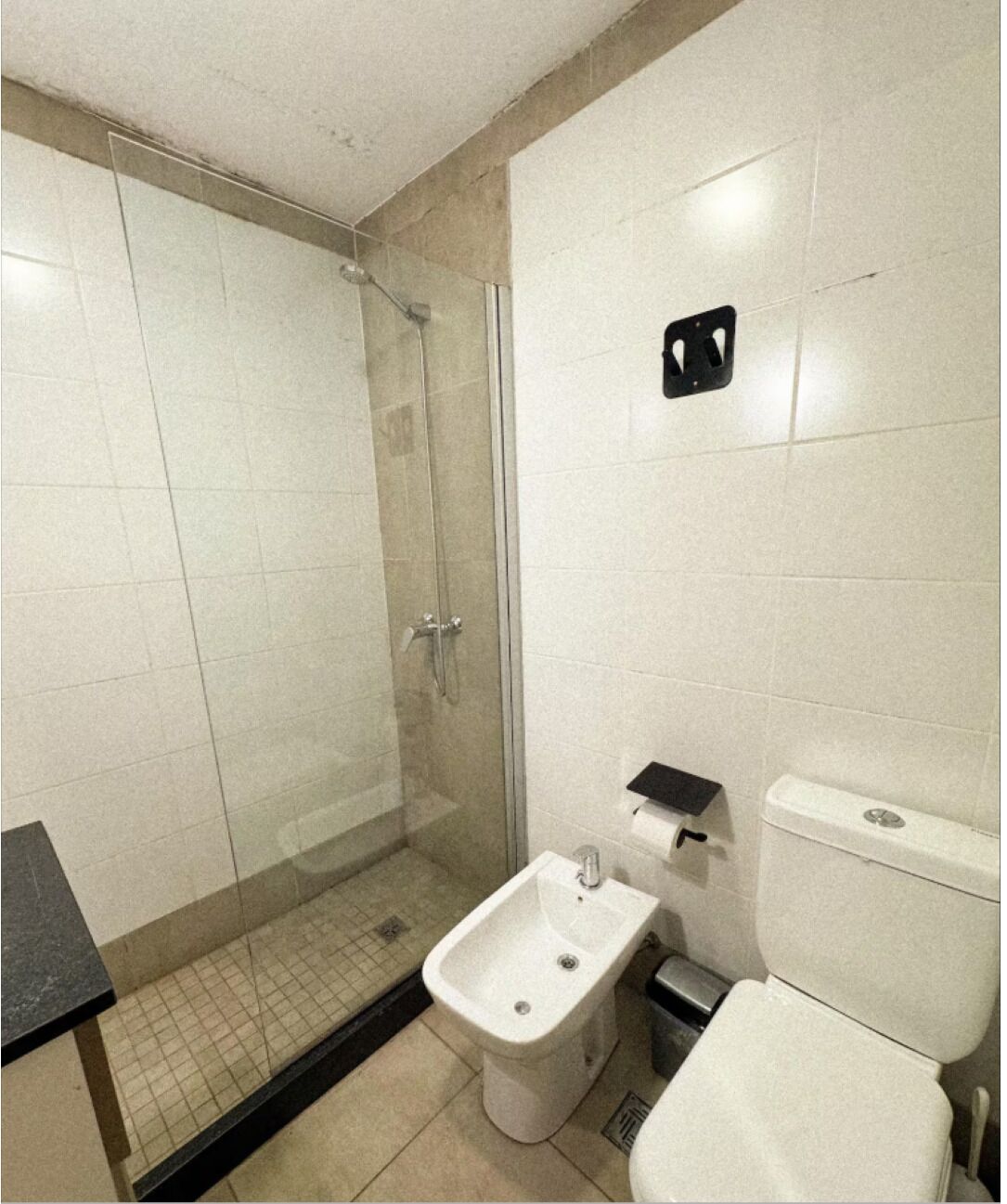 Ein kleines Badezimmer mit Dusche, Bidet, Toilette und Mülleimer.