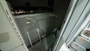 Un bany amb dutxa de vidre, penjador de tovalloles i suport de paper higiènic.