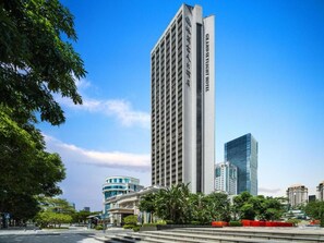 A tall hotel with a vertical facade, surrounded by greenery and other buildings. - Grandskylight Shenzhen Dapeng (Shenzhen)