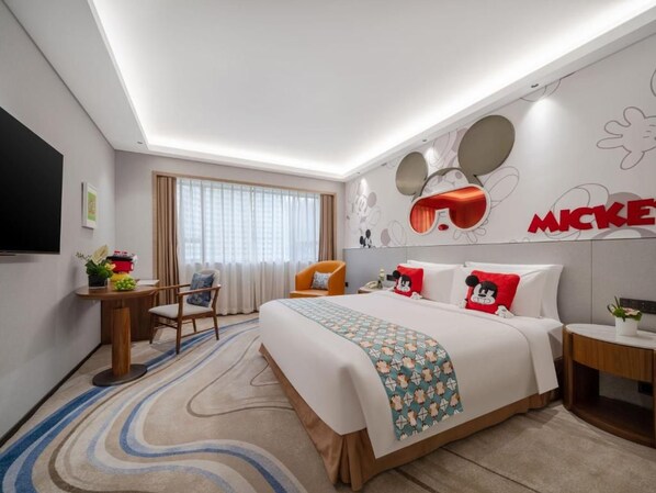 A hotel room with a bed, a desk, a chair, a TV, and Mickey Mouse-themed decor. - Grandskylight Shenzhen Dapeng (Shenzhen)