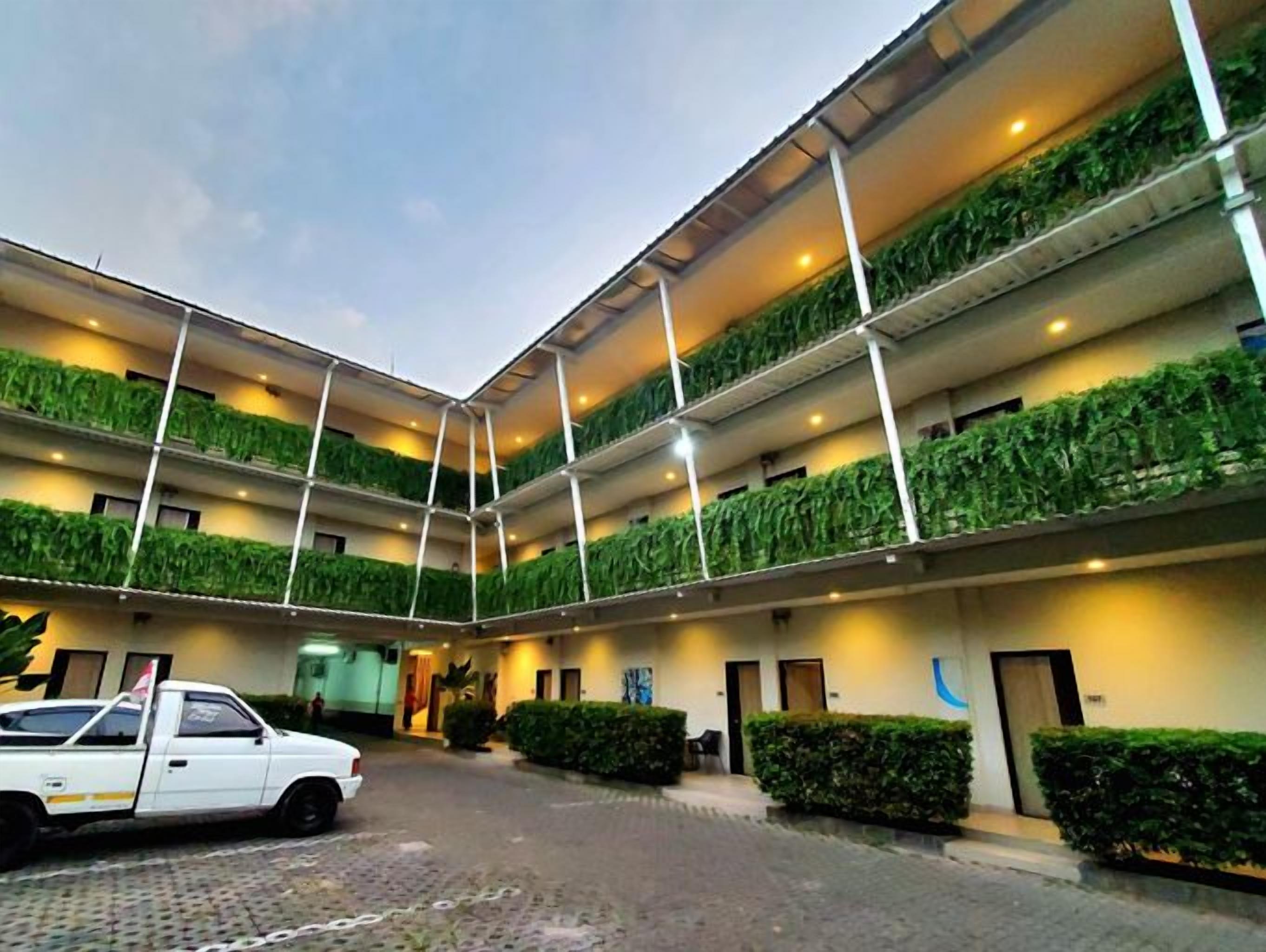 A multi-level building with a courtyard, a white pickup truck parked outside, and a clear sky.