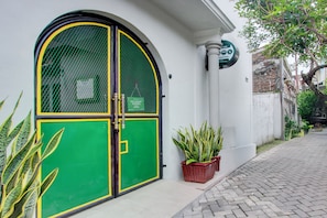 Un edificio con una puerta verde y amarilla, plantas en macetas y un letrero que indica un hotel.