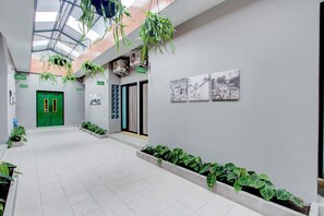 Ein geräumiger Korridor mit einer grünen Tür, hängenden Pflanzen und gerahmten Bildern an den Wänden.