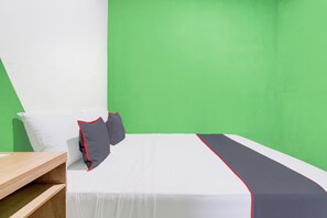 A bed with white bedding and red trim, a wooden nightstand, and a green wall. - Hotel O Yogyakarta Near Jalan Malioboro (Yogyakarta)