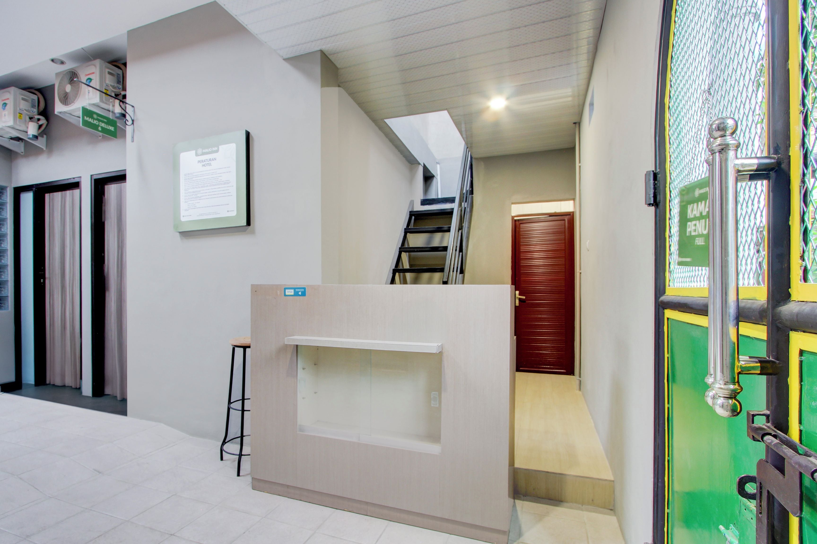 A hotel reception area with a reception desk, a staircase, and a door marked "KAMIN PENUN".