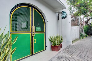 Un edificio con una puerta verde y amarilla, plantas en macetas y un letrero que indica un hotel.