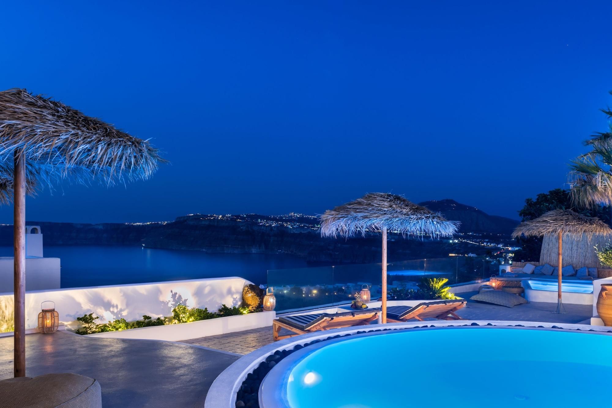 A poolside area with lounge chairs, a pool, and a view of the coastline at night.