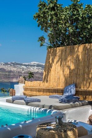 A poolside area with lounge chairs and a view of a mountainous landscape. - Summer Lovers Villa (Santorini)