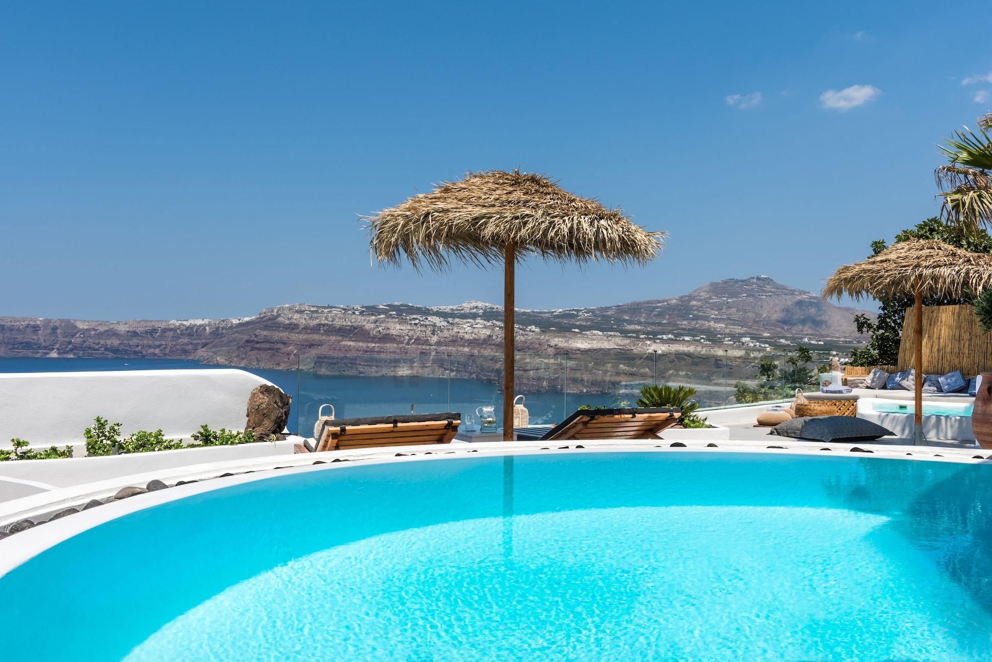 A clear blue pool with lounge chairs and a thatched umbrella, overlooking a scenic coastline.
